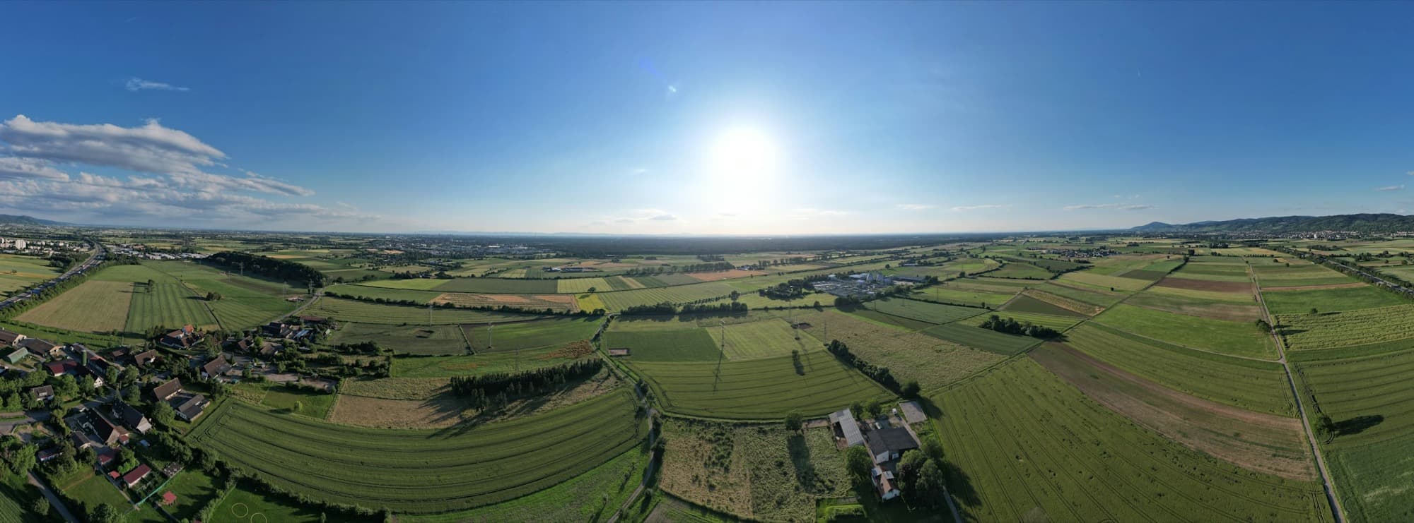 Weite Agrarlandschaft mit Feldern, Wiesen und einem Dorf aus der Luft