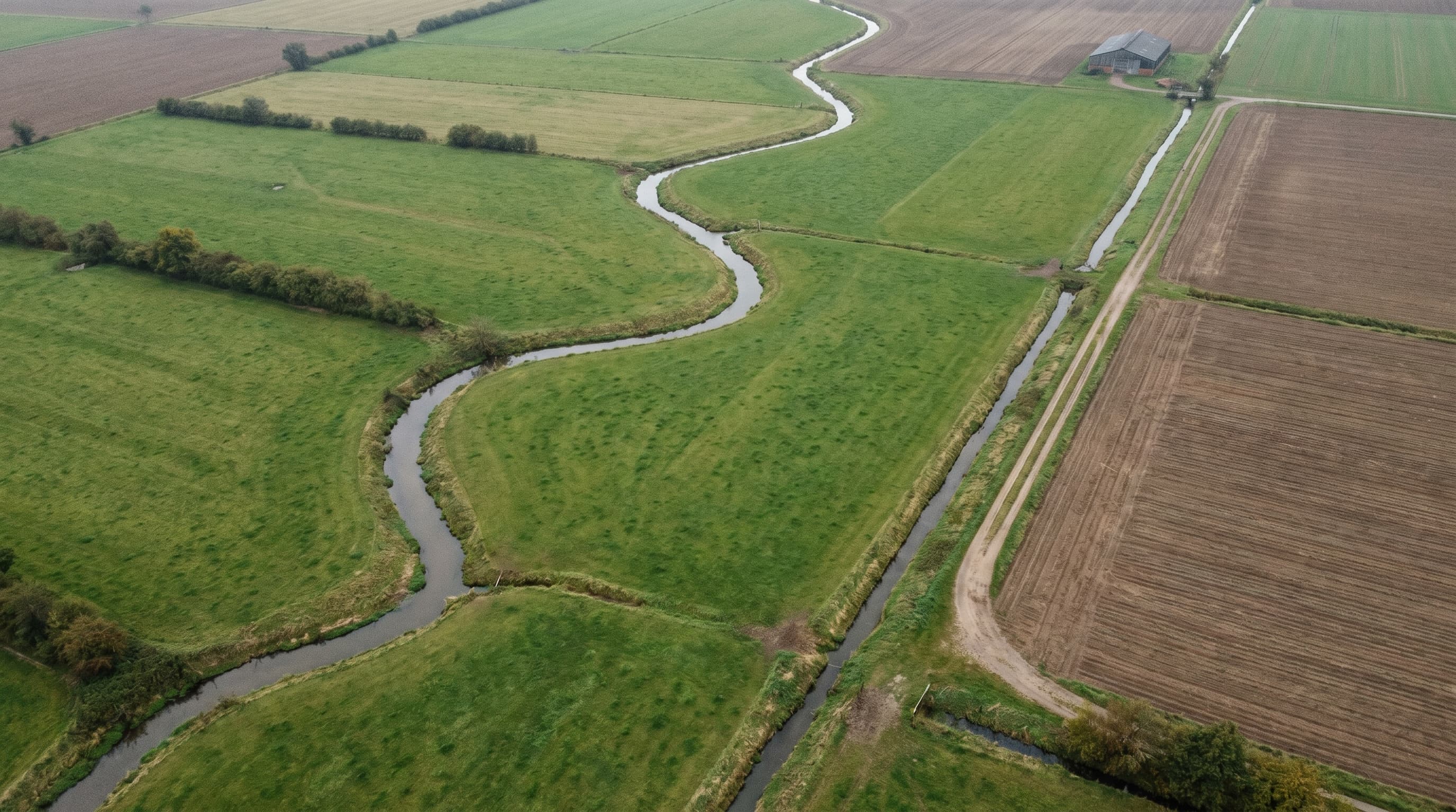 Acker mit kleinem Bachlauf und Graben aus der Vogelperspektive